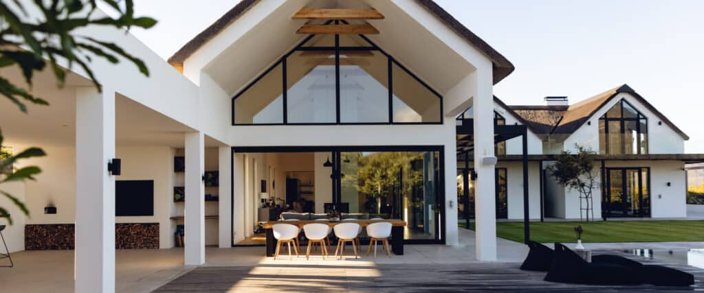 Villa moderne au toit de chaume avec terrasse, salle à manger extérieure et piscine au design contemporain épuré.